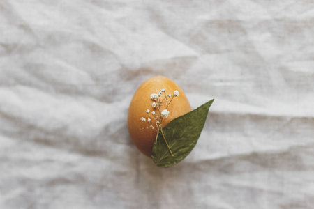 Easter egg decorated with dry flower on rustic linen napkin flat lay. Creative natural eco friendly decor of easter eggs. Happy Easter minimalist greeting card with space for textの写真素材