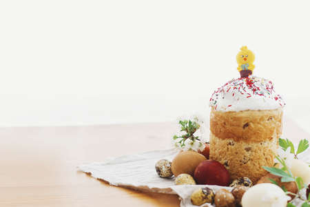 Delicious homemade Easter bread, stylish easter eggs, blooming spring flowers on rustic table in...