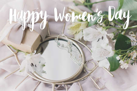 Happy women's day greeting card. Handwritten greetings on stylish gift box, jewelry, spring flowers...