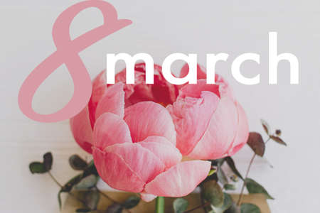 8 march text sign on peony and eucalyptus blooming from craft envelope on white wood. Happy women's...