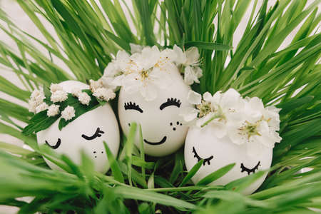 Eco friendly zero waste holiday. Easter eggs with drawn sleeping faces in floral wreaths in green...
