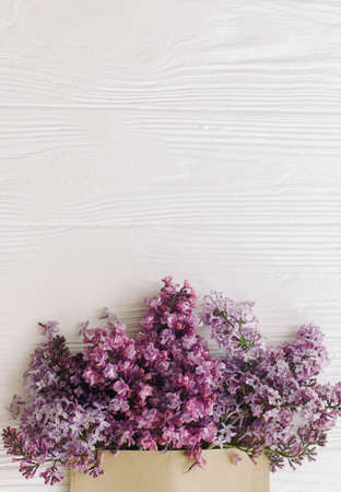 Happy mothers day and womens day. Creative floral greeting card. Spring lilac flowers blooming from craft envelope flat lay on white wood with space for text. Flower delivery and Hello springの写真素材