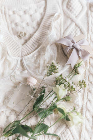 Stylish lace lingerie, perfume bottle, modern jewelry and gift box on cozy beige sweater with spring...
