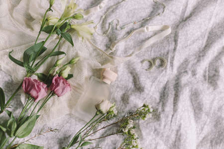 Stylish lace lingerie, modern jewelry, perfume bottle and spring flowers on bed. Soft trendy feminine image, sensual mood at home concept. Happy Women's day. Woman essentials, fragranceの写真素材
