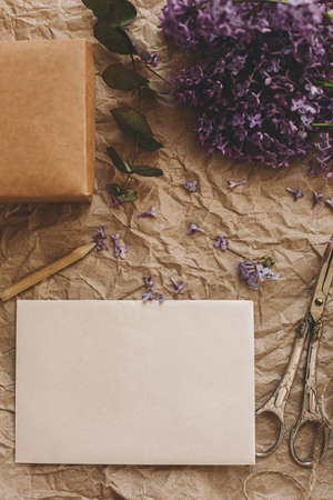Stylish card, beautiful lilac flowers, gift, vintage scissors, pencil and twine on rustic background, top view. Rural still life. Greeting card template, space for text.の写真素材