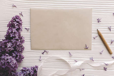 Beautiful lilac flowers, greeting card and ribbon on white rustic wooden background, flat lay with...