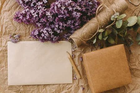 Stylish card, beautiful lilac flowers, gift, pencil and twine on rustic background, top view. Rural still life. Greeting card template, space for text.の写真素材