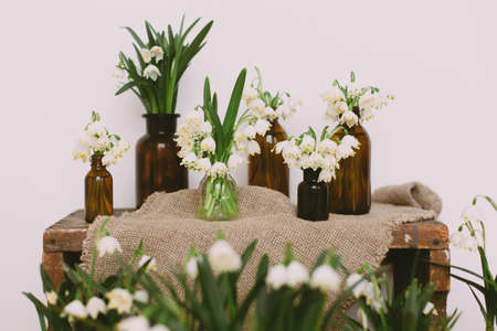 Spring white flowers in retro glass bottles on rustic linen cloth and wood in room. Rural still...