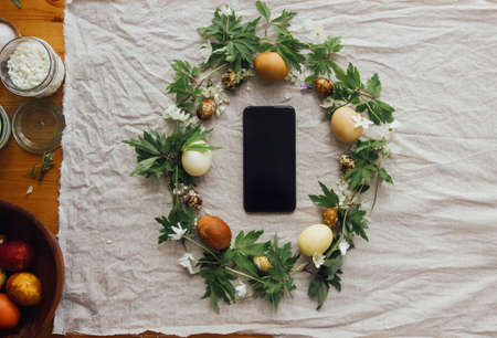 Easter rustic wreath and phone with blank screen, flat lay with space for text. Stylish easter eggs...