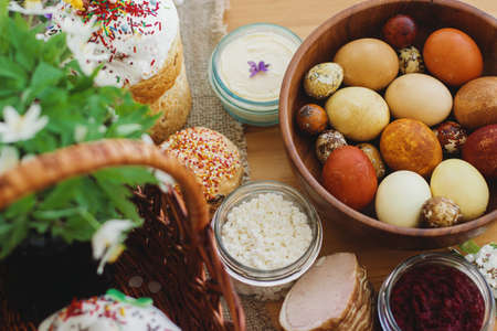 Stylish easter eggs, homemade Easter bread, delicious traditional Easter food in wicker basket and...