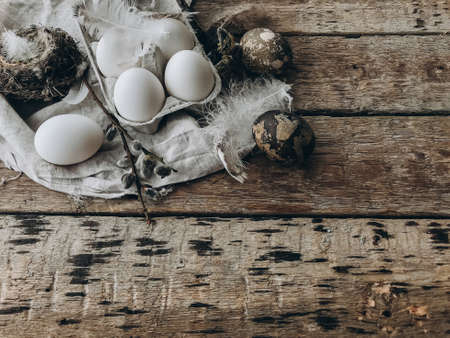 Natural easter eggs, feathers, pussy willow branches, bird nest on rustic cloth on aged wooden...