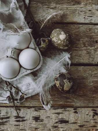 Easter rustic flat lay. Natural easter eggs, feathers, pussy willow branches, bird nest on rustic cloth on aged wooden table. Stylish easter rural still life, brown and grey colorsの写真素材