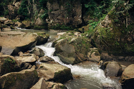 Beautiful view at river with rocks in mountains. Travel and wanderlust. Little waterfall on river and flowing water with stone cascade among woods. Peaceful tranquil momentの写真素材