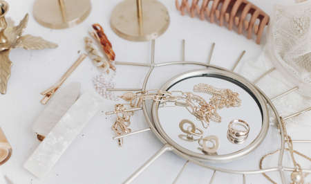 Modern summer accessories. Golden jewellery on boho mirror, barrettes, hair clips, cosmetics,...