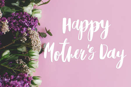 Happy mother's day greeting card. Happy mother's day text and lilac and roses fresh colorful border on bright pink paper flat lay. Stylish floral greetings. Handwritten lettering. Mothers dayの写真素材