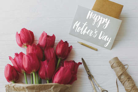 Happy mother's day greeting card. Happy mother's day text on card and red tulips, gift, pencil,...