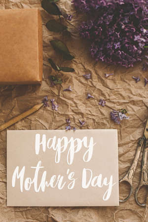 Happy mother's day. Happy mother's day text on card and lilac flowers, gift, pencil, vintage scissors on rustic background. Stylish floral greeting card. Handwritten lettering. Mothers dayの写真素材