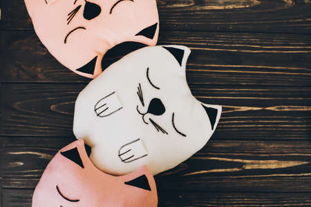 Cute cat shaped pillows on wooden background,top view. Pink and white adorable cushions in shapes of cats on rustic tableの写真素材
