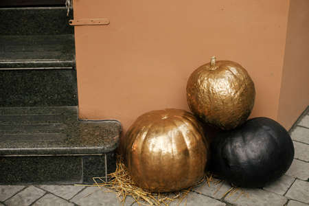 Golden and black pumpkins in city street, festive holiday decor of storefronts and buildings. Halloween modern decoration outdoor. Happy halloween. Autumn market in town, painted pumpkinの写真素材