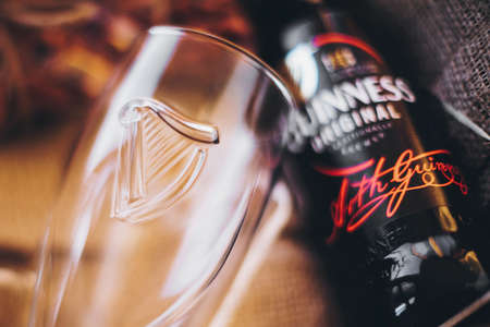 Lviv, Ukraine - December 1, 2017: Guinness beer bottle, glass cup on burlap in gift box. Soft focus....