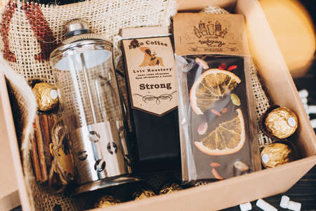Lviv, Ukraine - December 1, 2017: Roasted Coffee, french press and chocolate candy on straw in lights. Stylish coffee gift box for christmas, new year, birthday, fathers or mothers dayのeditorial素材