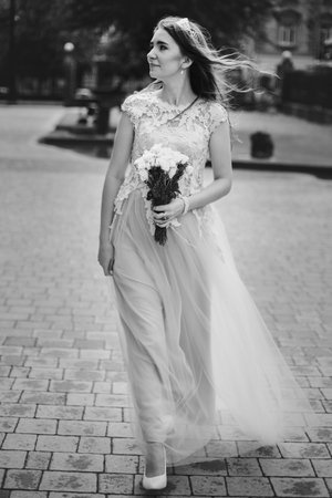 Beautiful happy bride in stylish vintage dress walking in sunny street on background of church....