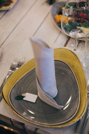 Stylish table setting, modern plate with card and napkin at provence wedding reception in...