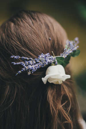 Beautiful lavender and rose flowers in bride hair close up. Stylish bride hairstyle with lavender flowers for provence wedding. Long hair with floral accessoriesの写真素材
