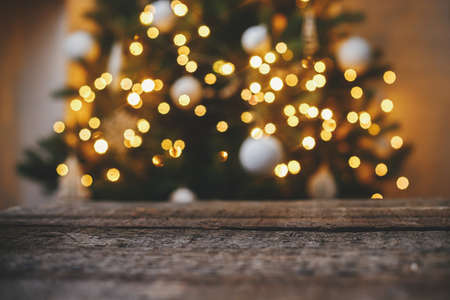 Christmas background. Rustic wood on background of christmas tree  lights golden bokeh. Space for text. Merry christmas and Happy Holidays!  Atmospheric christmas eveの写真素材