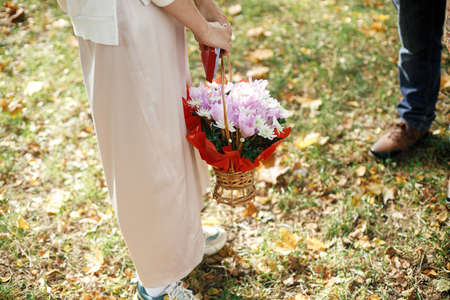 Stylish  woman in modern outfit holding basket of flowers and sweets after family...