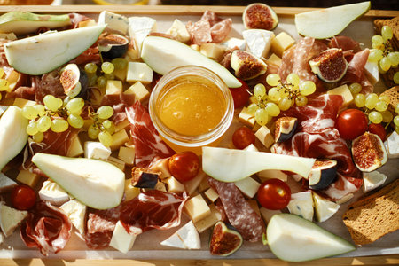 Charcuterie board with maasdam, camembert, brie, cheddar cheese and prosciutto, salami, figs,...