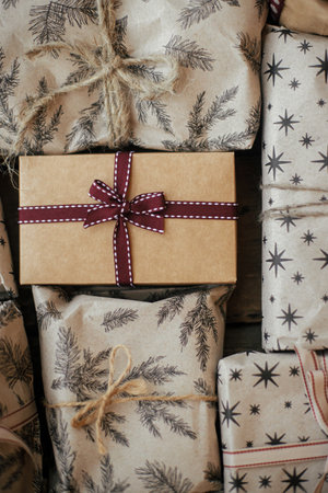 Stylish christmas gifts with ribbons on rustic wooden table flat lay. Xmas presents wrapped in craft paper with ribbons and threads. Zero waste eco friendly packaging. Merry Christmas!の写真素材