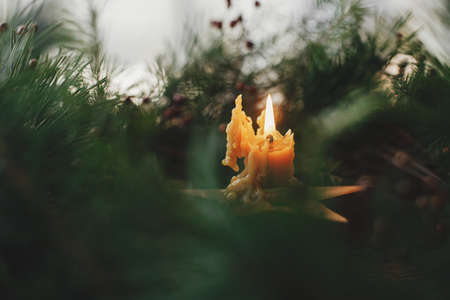 Merry Christmas and Happy holidays! Stylish rustic burning candle in christmas wreath on old wooden background. Christmas advent. Moody atmospheric time. Space for text.の写真素材