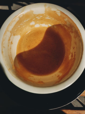 Top view of coffee foam in empty cup in sunny light on wooden table on cafe terrace. Fresh tasty breakfast in morning city. Aestheticsの写真素材