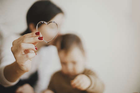 Lovely mommy daughter moments, happy family. Mother holding heart shaped cookie cutter close up, making together with little daughter christmas gingerbread cookies. Holiday preparationの写真素材