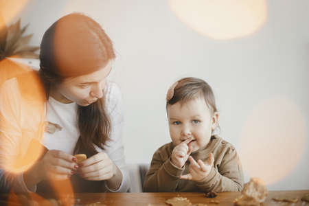 Family holiday preparations. Cute daughter and mother making christmas cookies on messy table, close up. Adorable toddler girl with mom cutting dough for gingerbread cookies. Moments togetherの写真素材