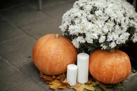 Pumpkins, candles and autumn flowers on sidewalk in city street, festive holiday decor. Halloween festive decoration outdoor. Happy halloween. Autumn market in town. Copy spaceの写真素材