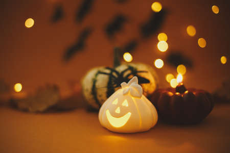 Happy Halloween. Pumpkin, glowing jack o lantern, burning candle, spider on dark orange background with magical lights and flying black bats. Atmospheric Halloween background. Space for textの写真素材
