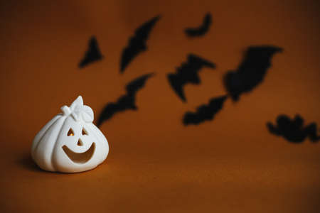 Halloween background. Jack o lantern pumpkin decoration on dark orange background with flying black bats. Happy Halloween. Greeting card with space for text. Trick or treatの写真素材