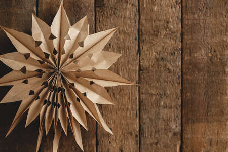 Stylish paper Christmas star hanging on rustic old wooden background. Season's greeting card with space for text. Modern sweden paper star. Merry Christmas and Happy Holidays!の写真素材