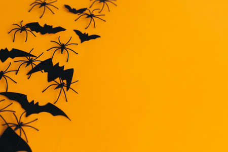 Happy Halloween. Spiders and bats layout on orange background with space for text. Season's greeting card. Halloween decorations border on yellow paper. Minimalistの写真素材