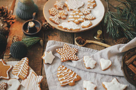 Christmas gingerbread cookies on rustic table with napkin, candle, decorations, spices. Atmospheric moody image. Stylish decorated christmas gingerbread cookies. Merry Christmas and Happy Holidays!の写真素材