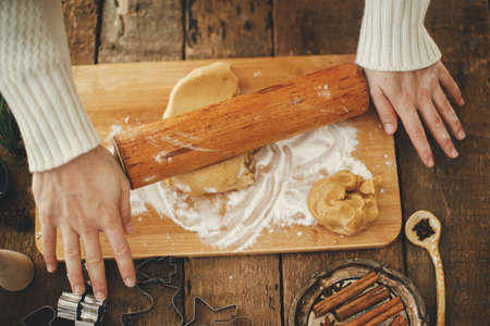 Hands rolling out gingerbread dough with wooden rolling pin for christmas traditional cookies....
