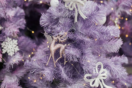 Stylish glitter reindeer toy on modern purple christmas tree with ornaments and lights in store front or building facade. Christmas festive street decor for winter holidays. Merry Christmasの写真素材