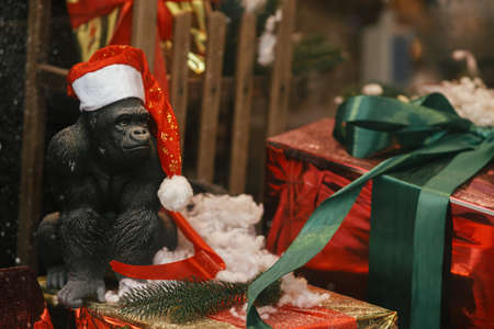 Gorilla in santa hat sitting at big christmas wrapped presents, decoration of window shop in european city street. Christmas festive street decor for winter holidays. Happy Holidays!の写真素材