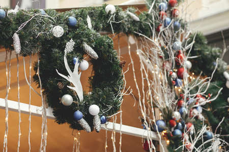 Stylish modern christmas wreath with white and blue ornaments, reindeer antlers, spruce branches. Christmas festive street decor for winter holidays fair in european city street. Merry Christmas!の写真素材