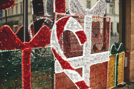 Stylish christmas decorations, candy cane and gift boxes with lights at window in european city street. Festive modern decor and illumination in shops and exterior for winter holidaysの写真素材