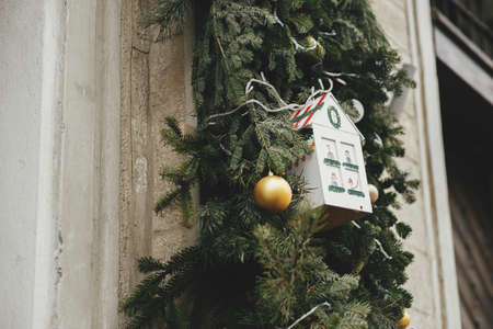 Stylish christmas little house and spruce branches decoration on building front or shop in european city street. Christmas festive street decor for winter holidays. Happy Holidays!の写真素材