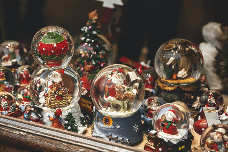 Merry Christmas! Stylish christmas snow globes in window shop. Christmas festive street decor in european city street for winter holidays. Magic little xmas scene, holiday winter fair.の写真素材