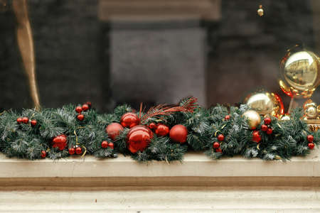 Stylish christmas spruce branches and red and gold baubles decoration on window of building or shop. Christmas festive street decor for winter holidays in european city street. Merry Christmas!の写真素材